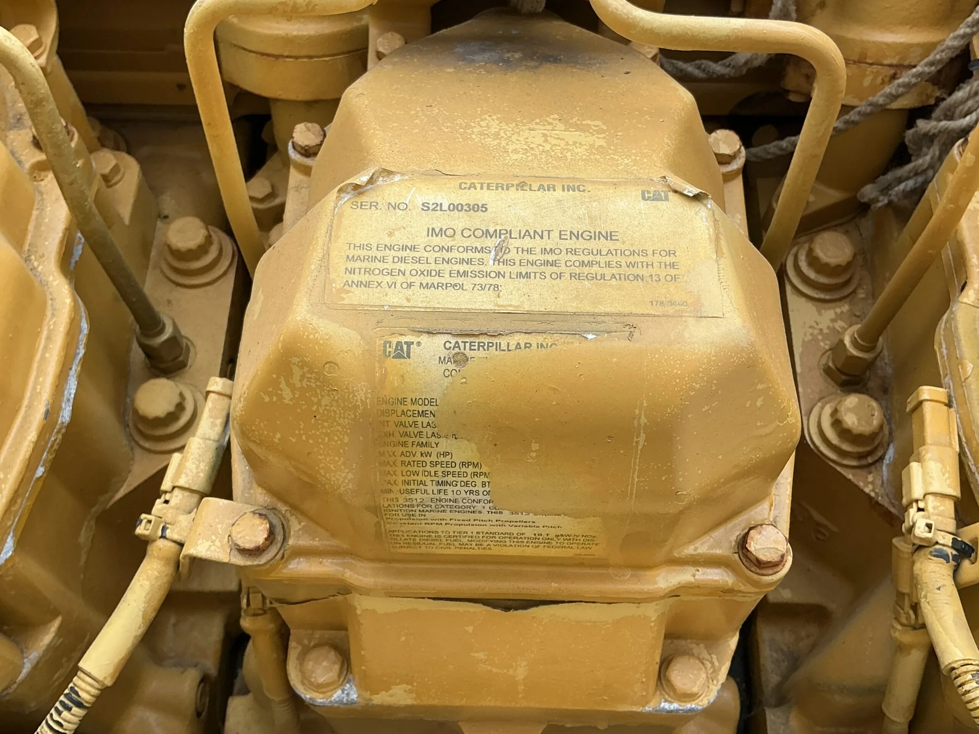 Caterpillar 3512B marine diesel engine, close-up of the yellow engine block showing an identification plate