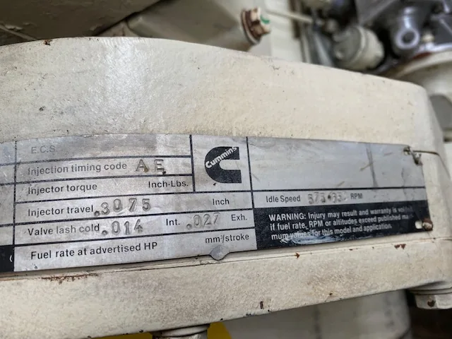 Cummins diesel engine data plate showing injection timing code AE, injector torque, idle speed RPM, and fuel rate at advertised HP