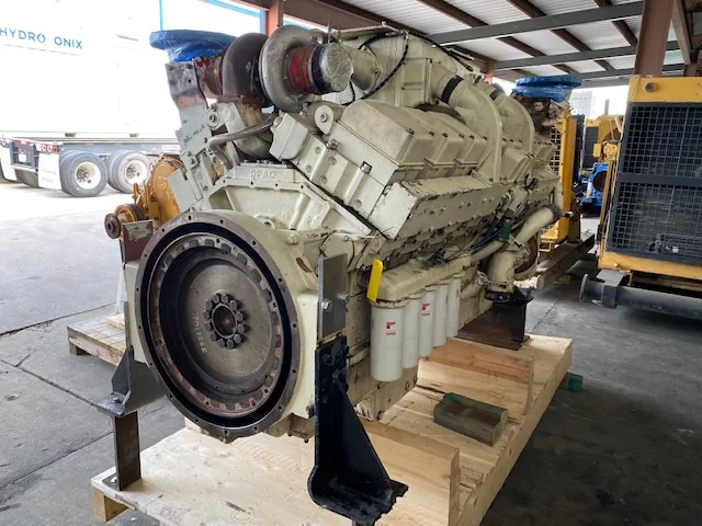 Industrial diesel engine on a wooden pallet; prominent round flywheel housing at the front and a turbocharger assembly on top