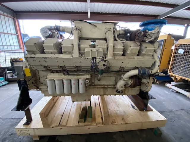 Large industrial diesel engine sits on a wooden pallet, beige with six vertical white filter canisters on the side and a blue-capped pipe
