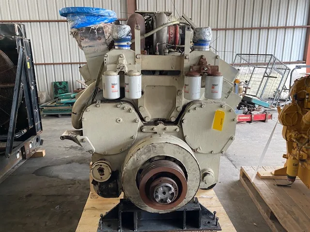 Industrial diesel engine with a large front flywheel housing; two white filter canisters atop the block and blue-wrapped intake pipes